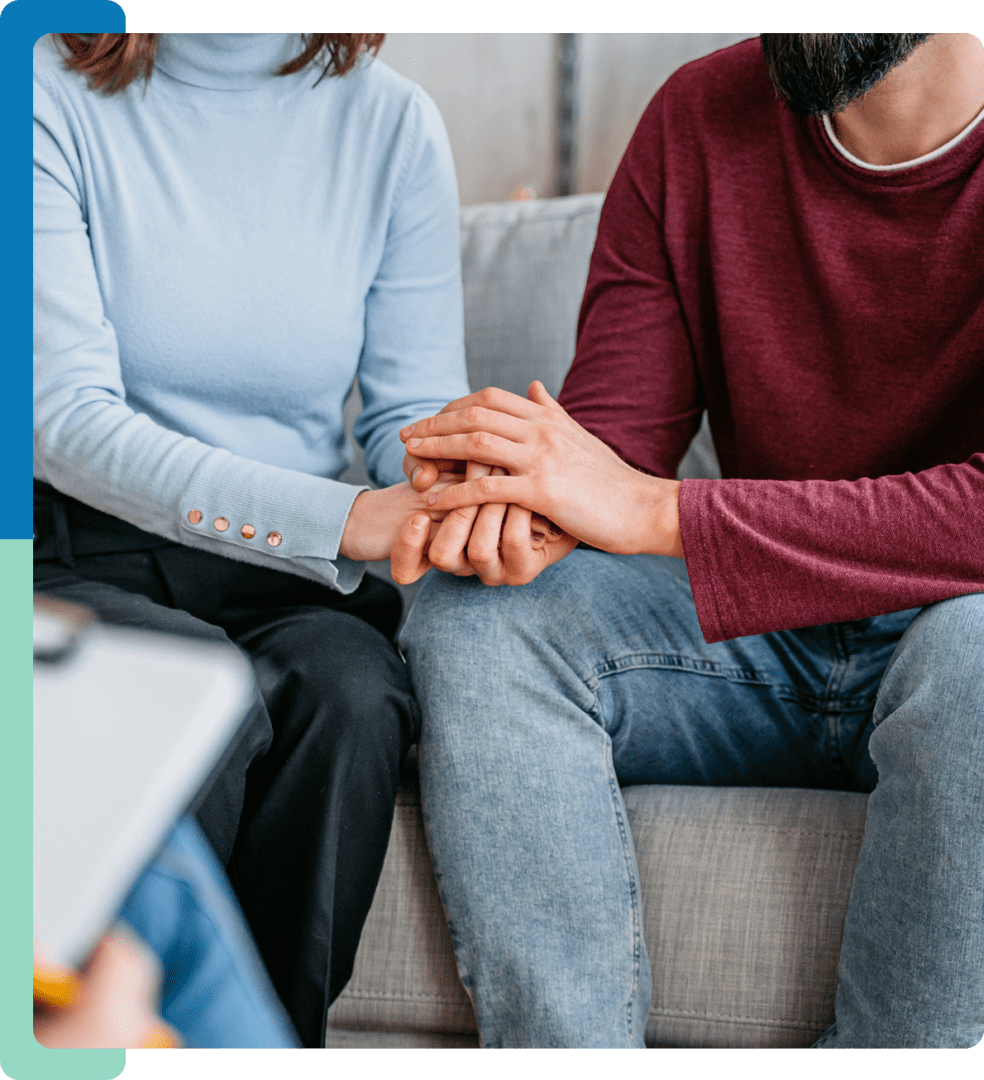 A man and woman holding hands on the couch.